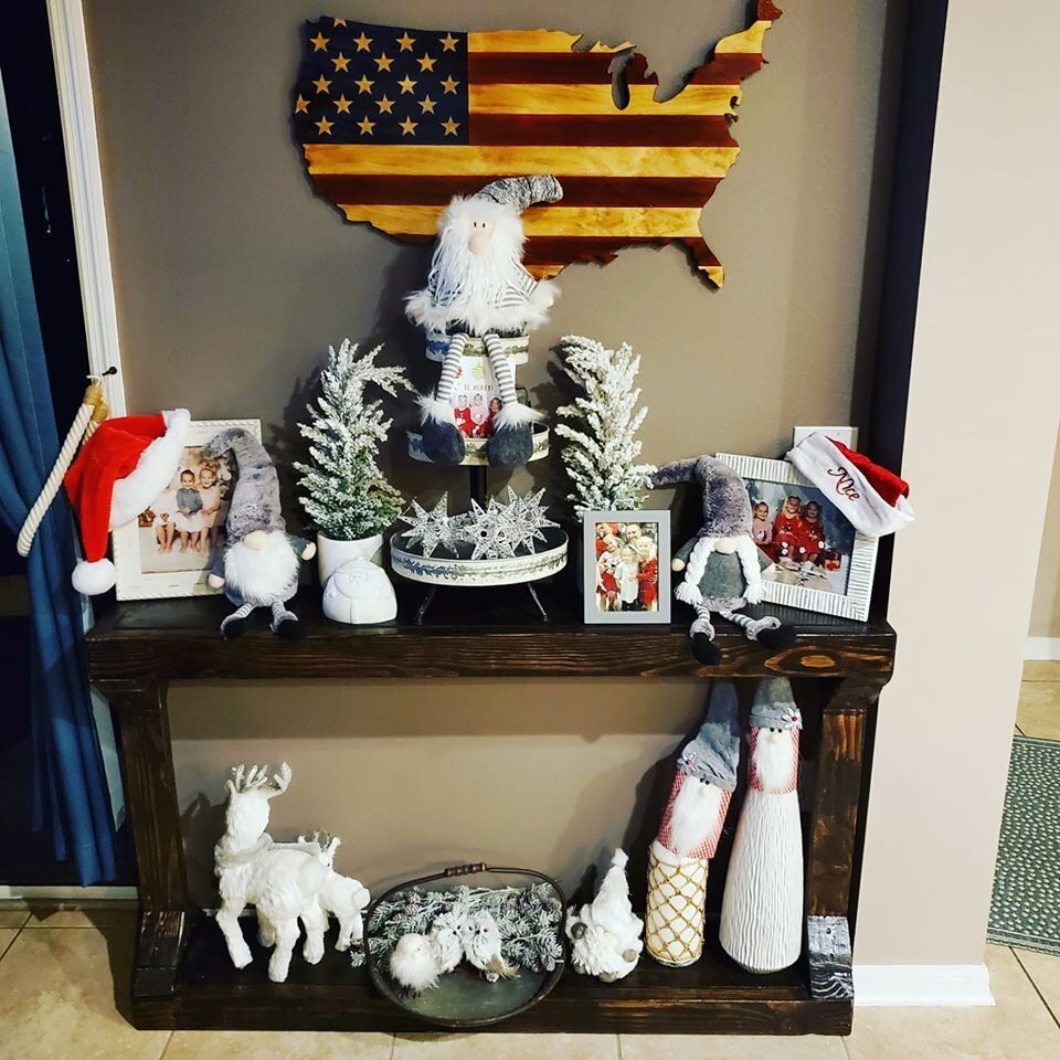 Christmas decorations on a wooden table, including gnomes, reindeer, and a wooden USA flag.