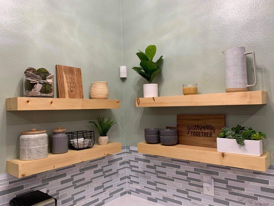Floating wooden shelves in a corner, displaying decorative items against green walls and a tiled backsplash.