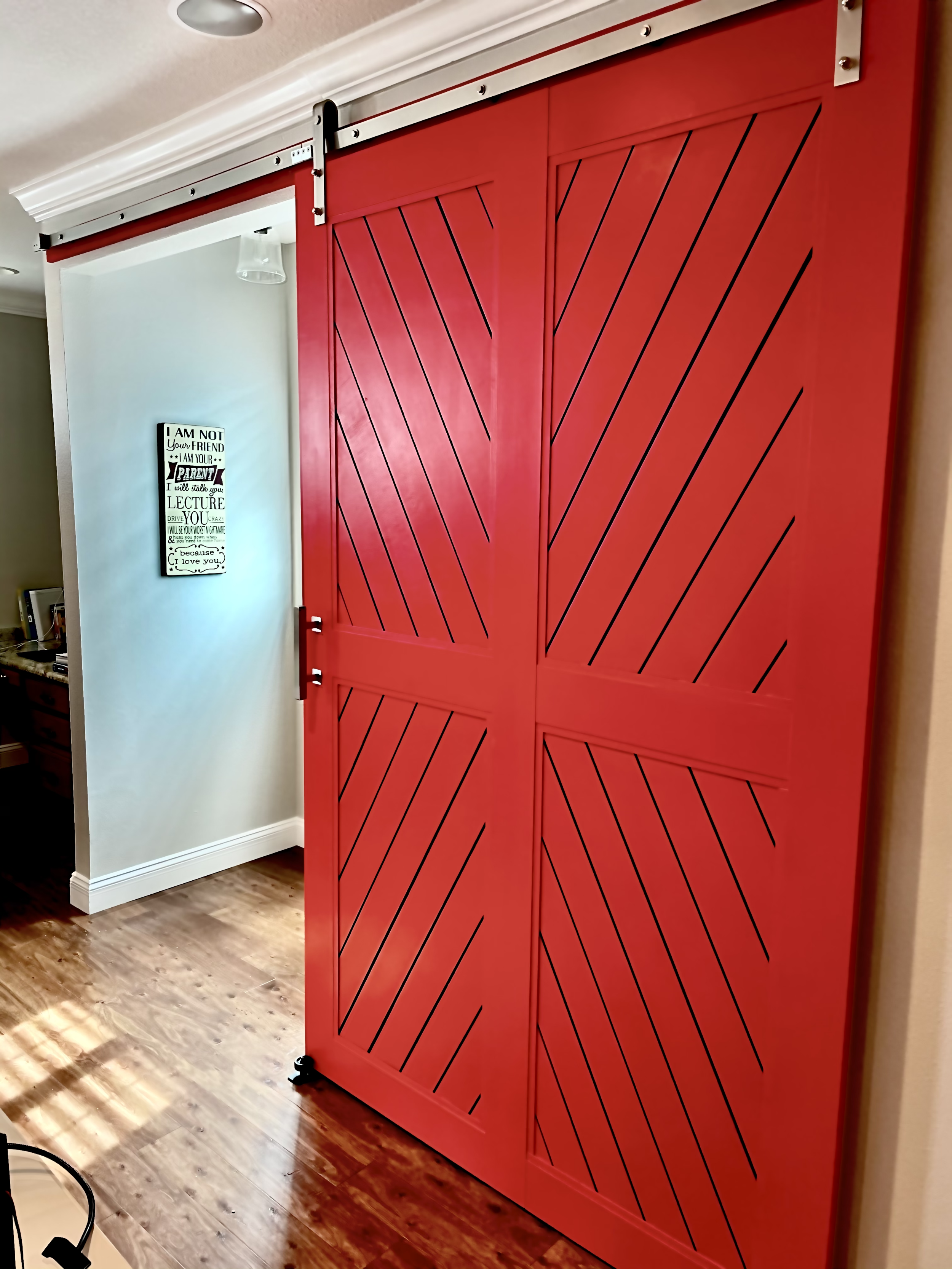 Bright red, diagonal-slashed barn doors on a track over a doorway, inside a home.