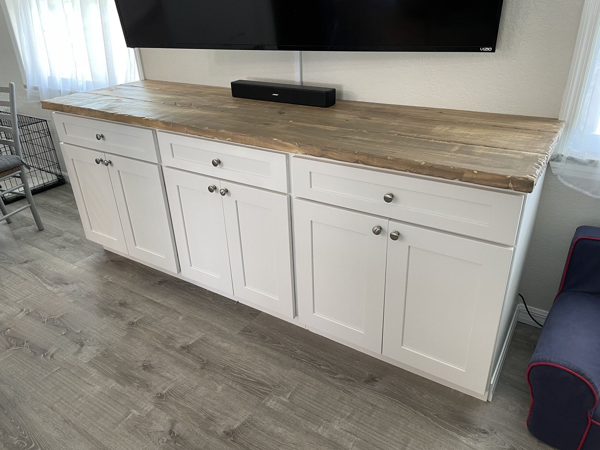 White cabinet with wooden countertop, TV mounted above.