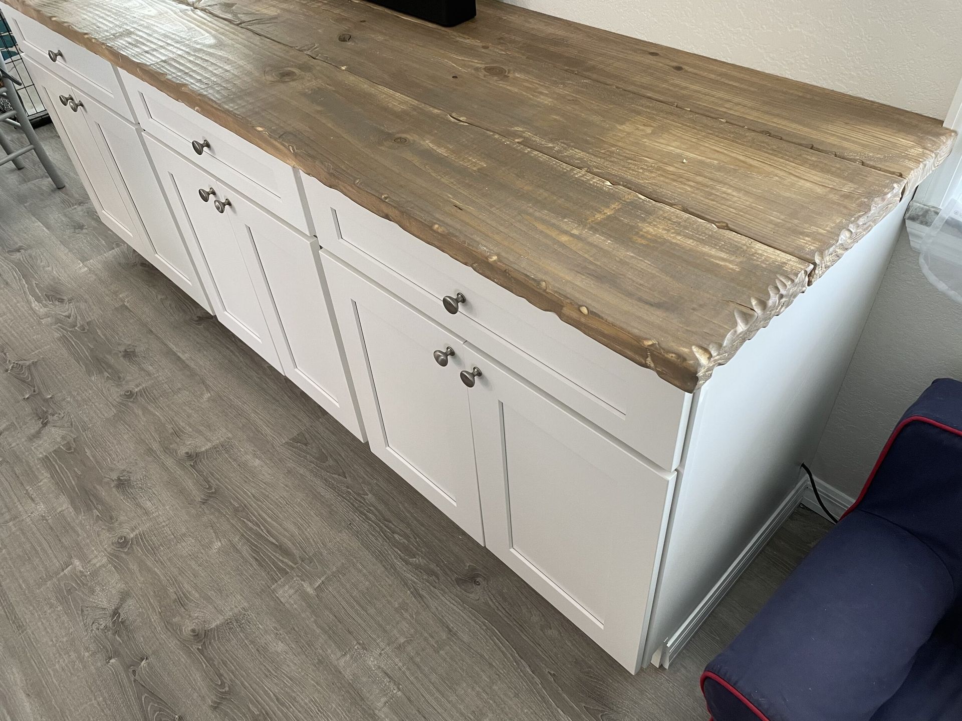 White cabinet with a wood countertop and chrome knobs.