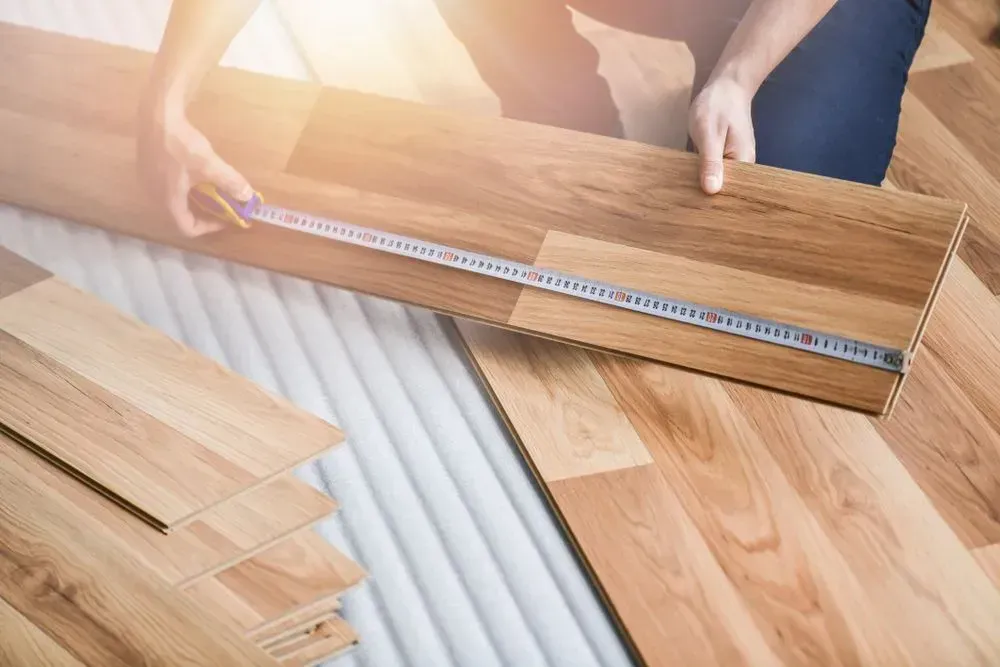 A Person is Measuring a Wooden Floor With a Tape Measure — Shane Callinan Floor Sanding In Bonny Hills, NSW