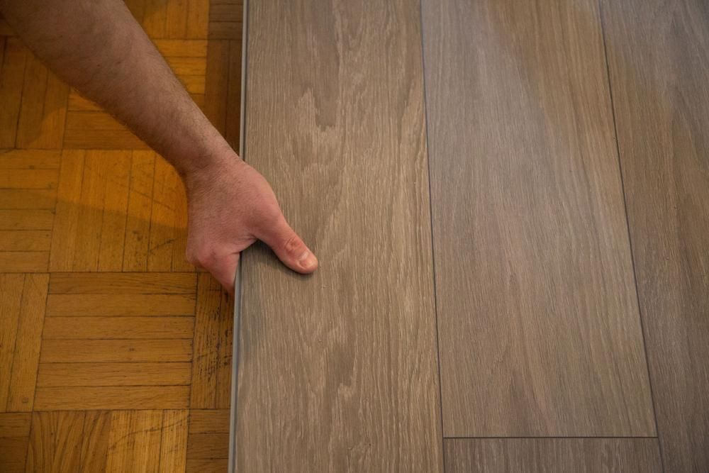 A Person is Holding a Piece of Wood on a Wooden Floor — Shane Callinan Floor Sanding In Kempsey, NSW