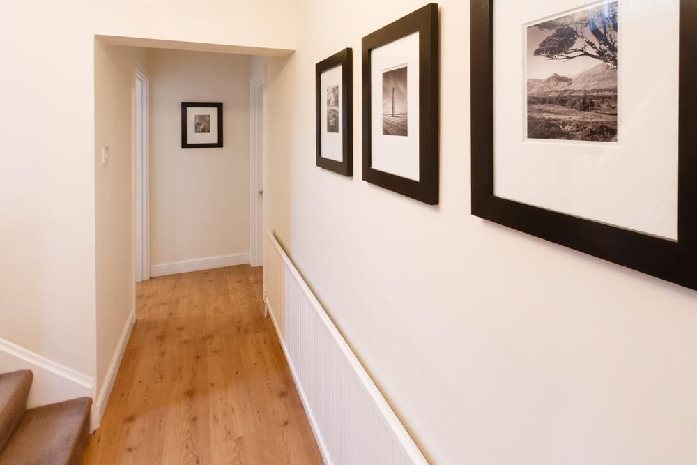 A Hallway With Pictures on the Wall and Stairs — Shane Callinan Floor Sanding In South West Rocks, NSW