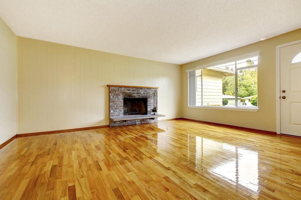 An Empty Living Room With Hardwood Floors and a Fireplace — Shane Callinan Floor Sanding In North Haven, NSW