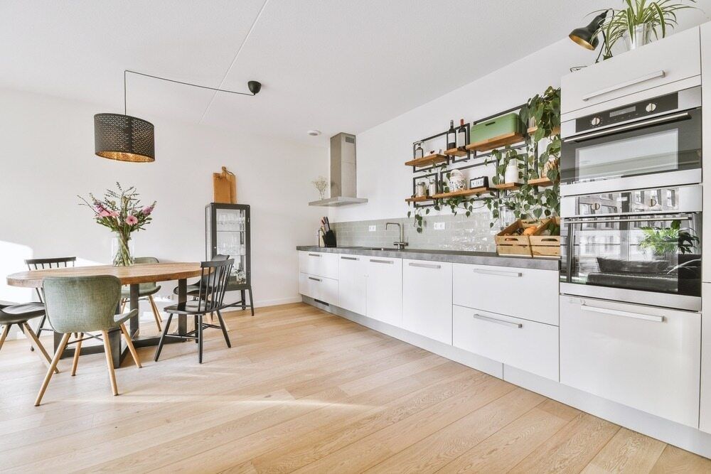 A Kitchen With White Cabinets , Wooden Floors , a Table and Chairs — Shane Callinan Floor Sanding In North Haven, NSW