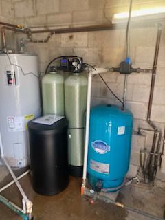 A room with a water heater , water filter , and pressure tank.