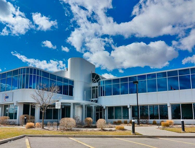 A large building with a lot of windows and a parking lot in front of it.
