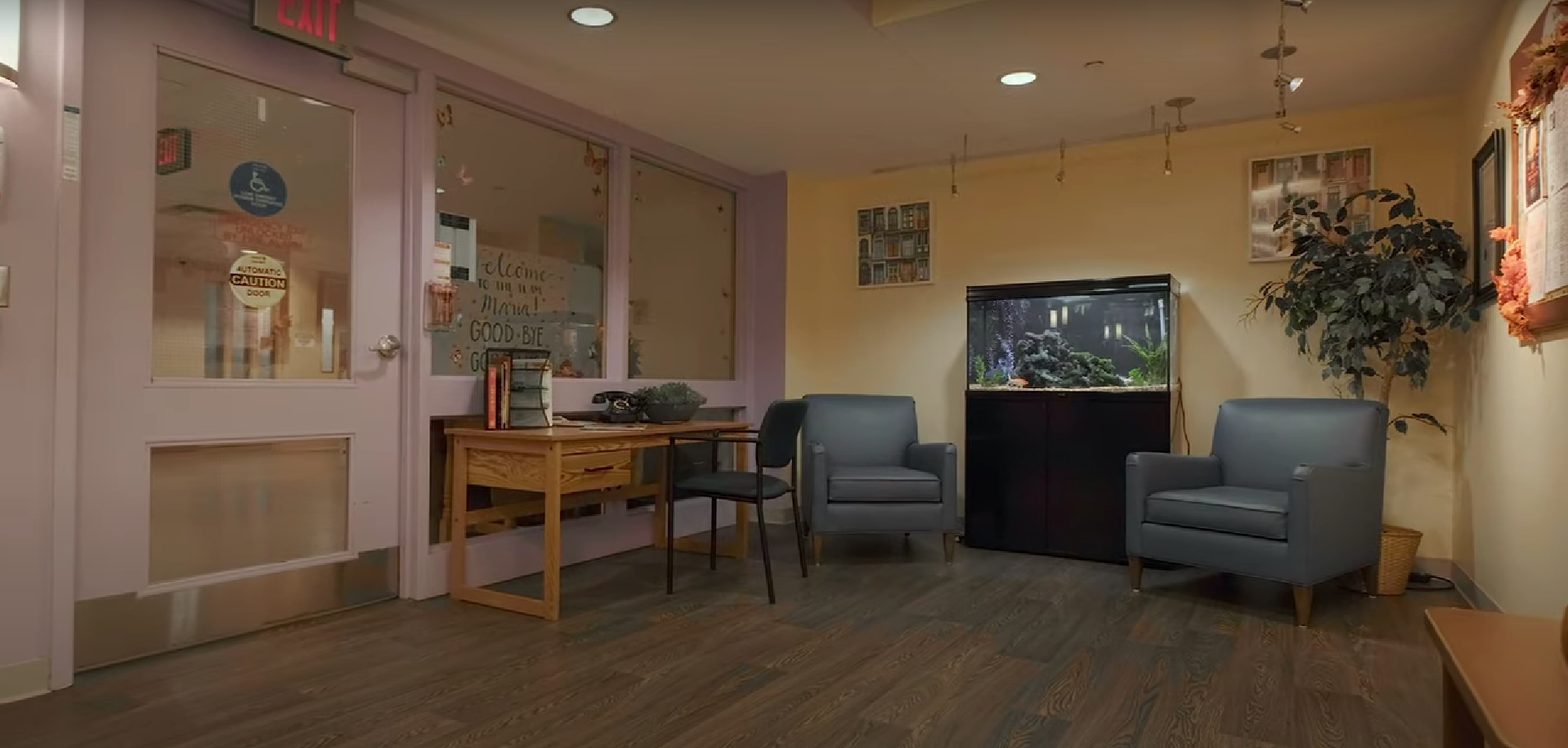 A waiting room with chairs , a desk , and an aquarium.