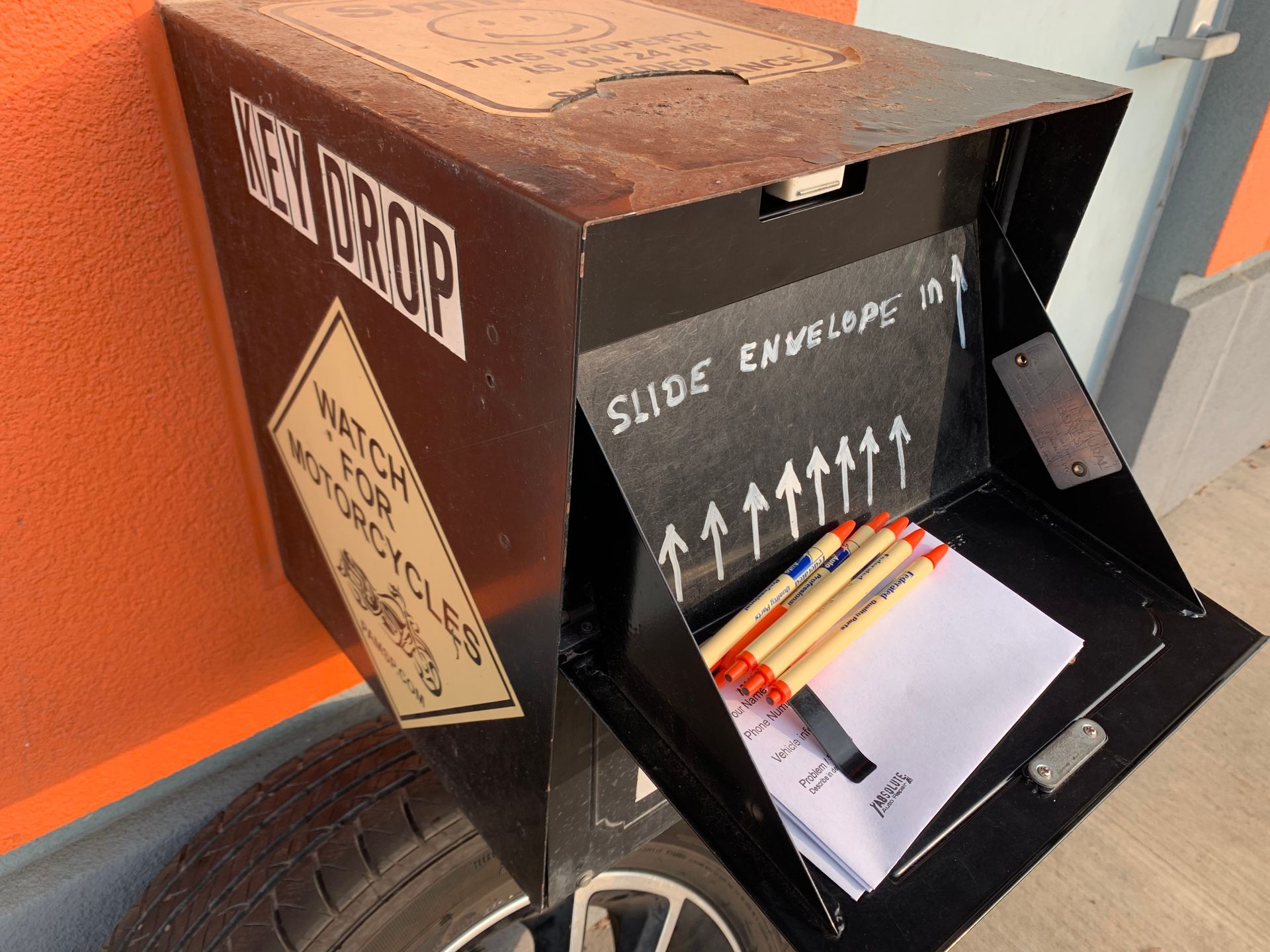 Black drop box with instructions to slide envelopes in; pens and paper inside. | Absolute Auto Repairs & Sales