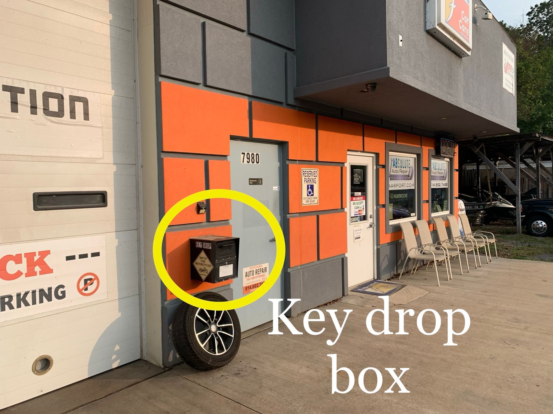 A key drop box attached to the wall of an auto repair shop with an orange and grey exterior. | Absolute Auto Repairs & Sales