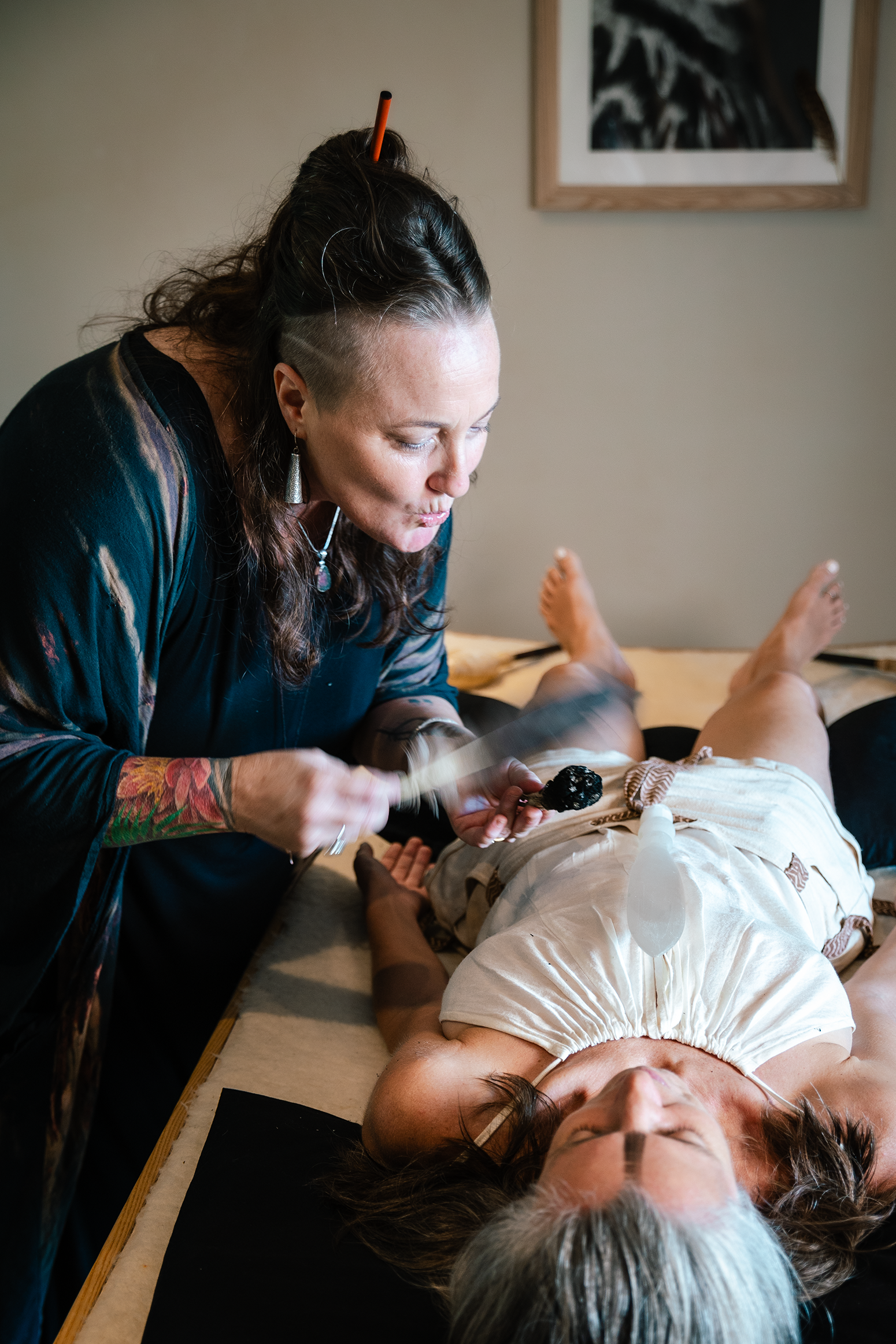A woman is laying on a bed while a woman is laying on a table.