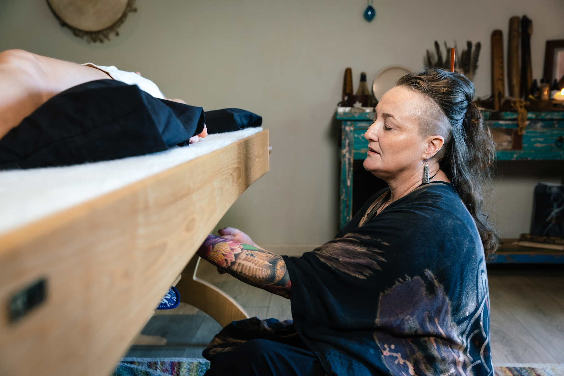 A woman is sitting at a table with a person laying on it.