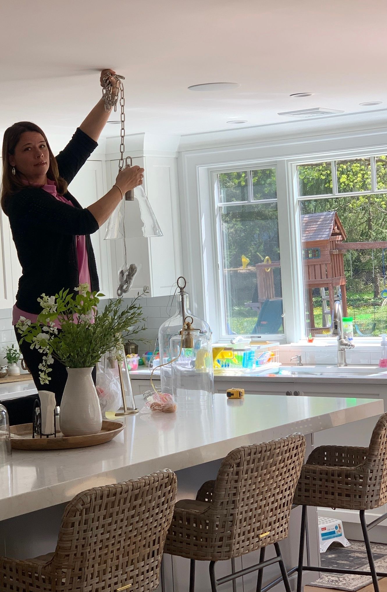 Woman with light brown hair, wearing a black top and silver earrings, looking toward the viewer.
