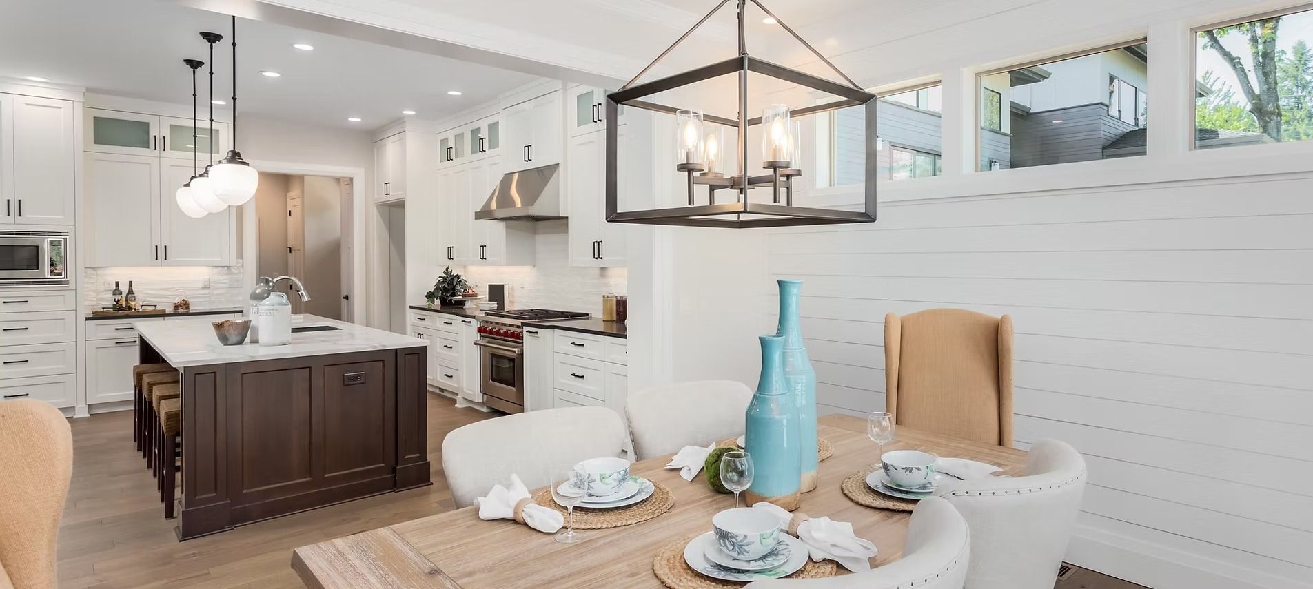Kitchen and dining room with a table set for a meal. Includes a kitchen island and modern light fixtures.