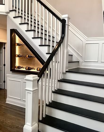 Staircase with black and white steps and a built-in wine rack. White spindles and black handrail.