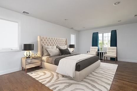 Spacious bedroom with a large bed, two chairs, and a window with blue curtains; neutral color scheme.