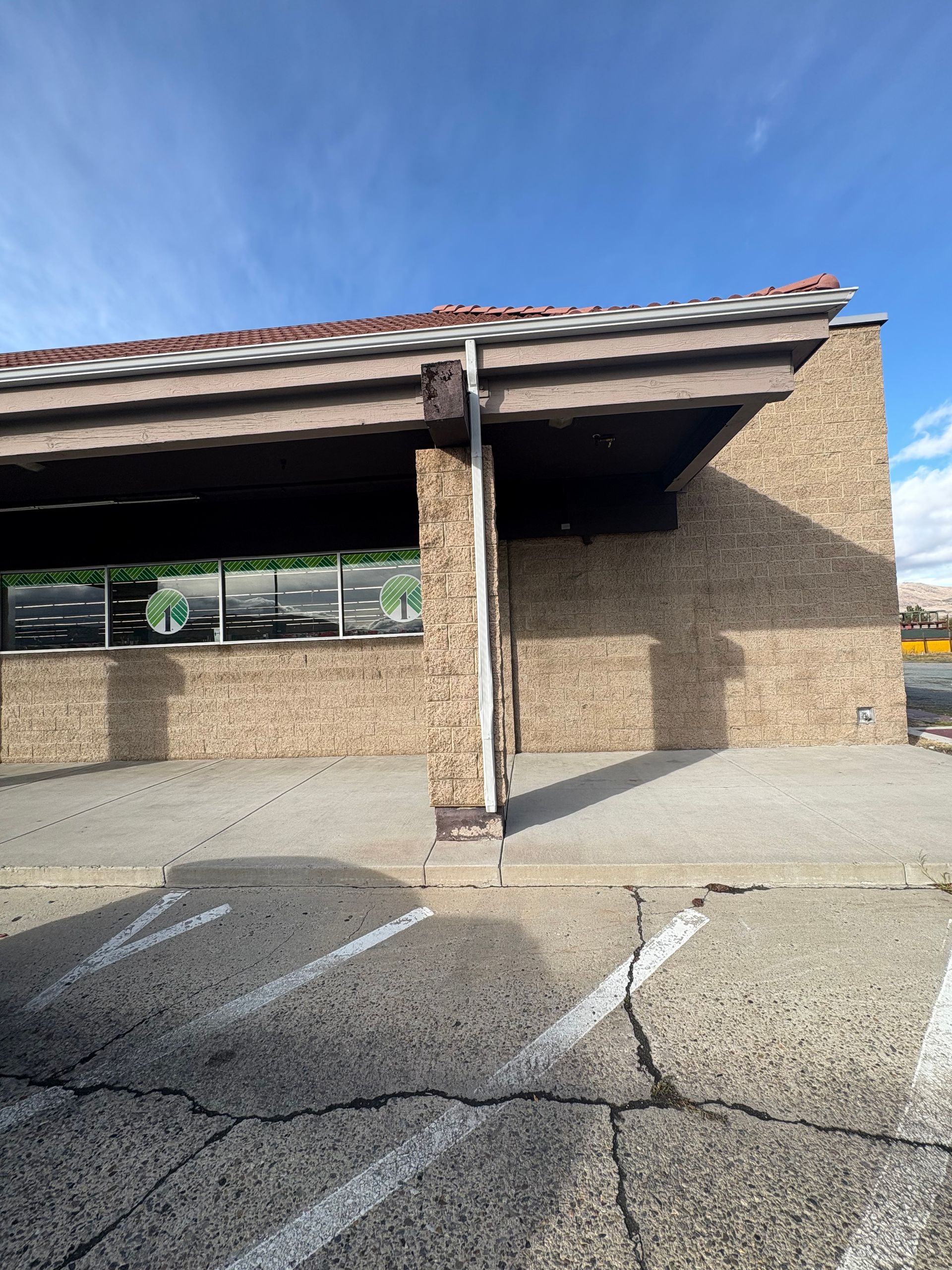 Brick building with a brown awning, sidewalk, and cracked pavement.