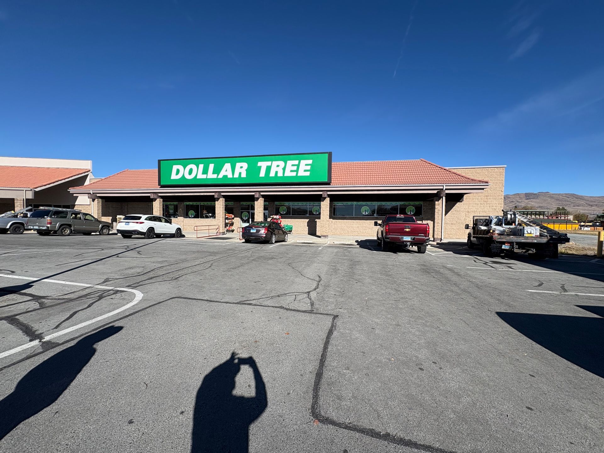 Dollar Tree store exterior with parked cars, blue sky.