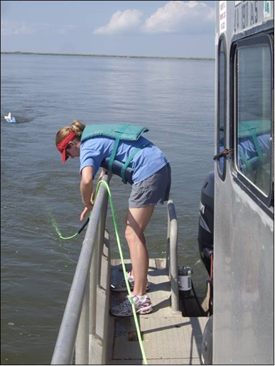 A woman in a life jacket is standing on a dock near the water - Baton Rouge, LA - Coastal Environments, Inc.