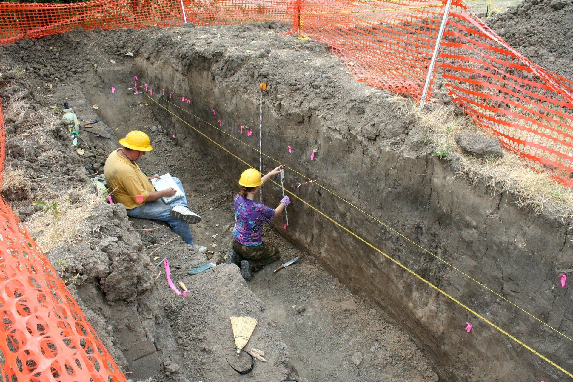 A man and a woman are measuring a hole in the ground - Baton Rouge, LA - Coastal Environments, Inc.