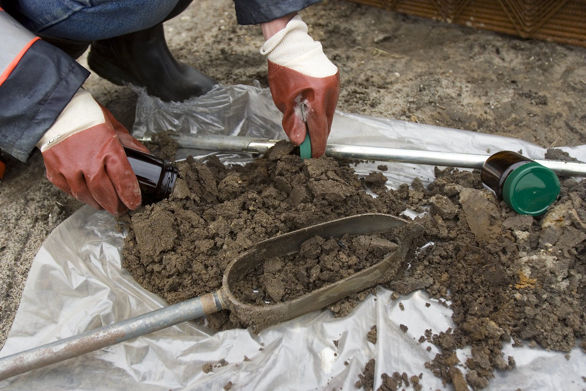 A person wearing red gloves is digging in the dirt - Baton Rouge, LA - Coastal Environments, Inc.