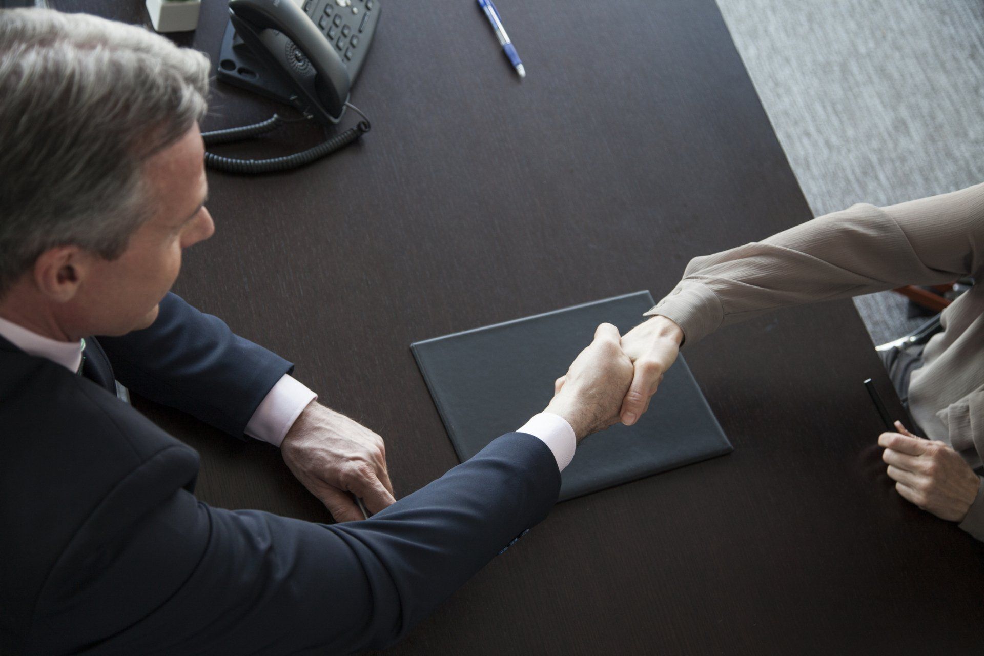 A man in a suit shakes hands with another man - Baton Rouge, LA - Coastal Environments, Inc.