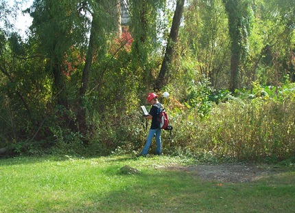 A man is mowing a lush green field in the woods - Baton Rouge, LA - Coastal Environments, Inc.