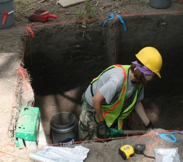 A man wearing a yellow hard hat is working in a hole - Baton Rouge, LA - Coastal Environments, Inc.