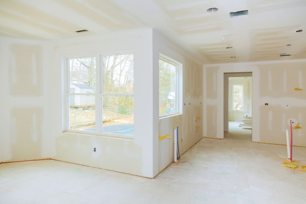 An Empty Room with Drywall and Windows in A House Under Construction — Iconic Construction Industries in Garbutt, QLD