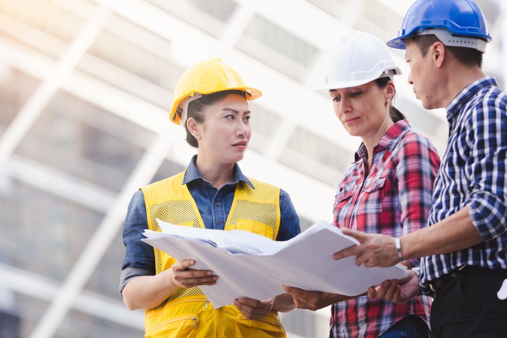 A Group of Construction Workers Are Looking at A Blueprint — Iconic Construction Industries in Garbutt, QLD