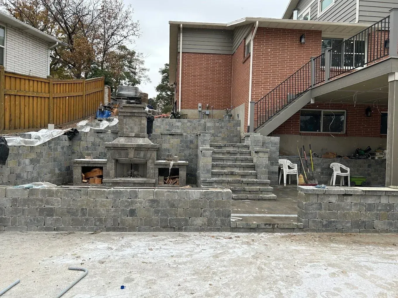 A brick house with stairs and a fireplace in the backyard.