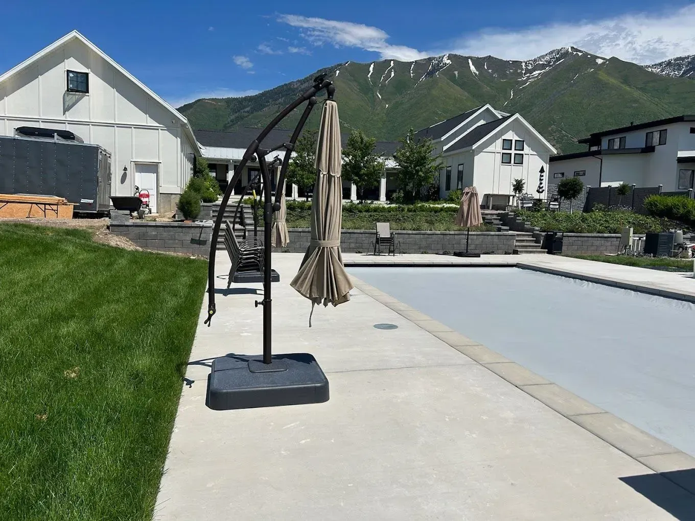 A swimming pool with umbrellas in front of a house with mountains in the background.