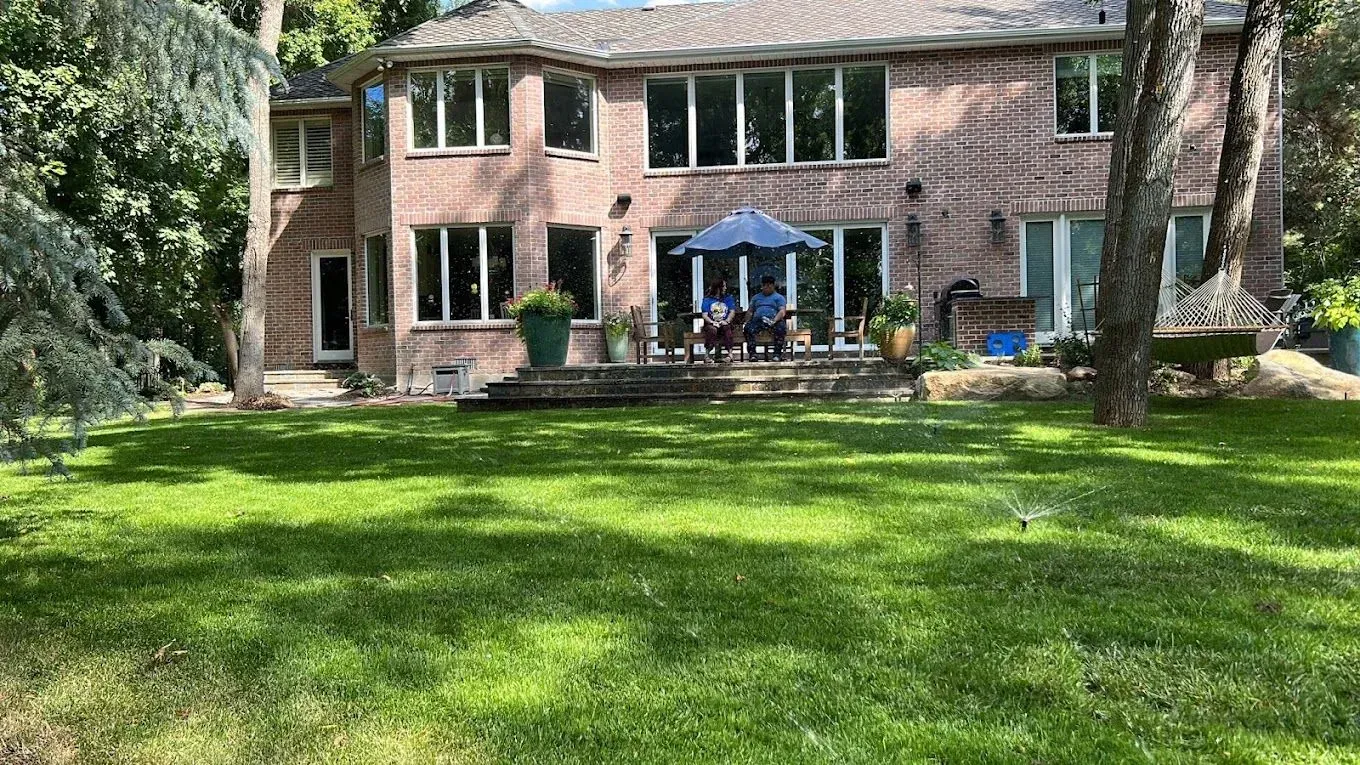 A large brick house with a lush green lawn in front of it.