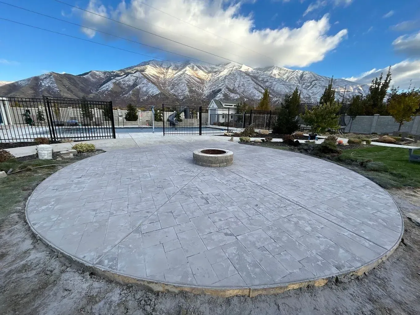 A circular patio with a fire pit in the middle and mountains in the background.