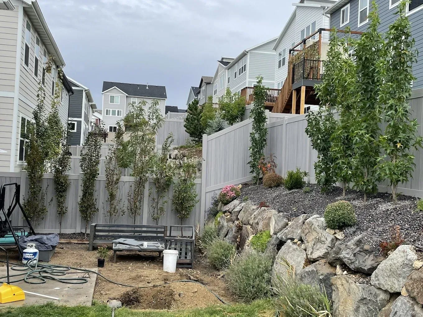 A backyard with a fence and a bench in front of a house.
