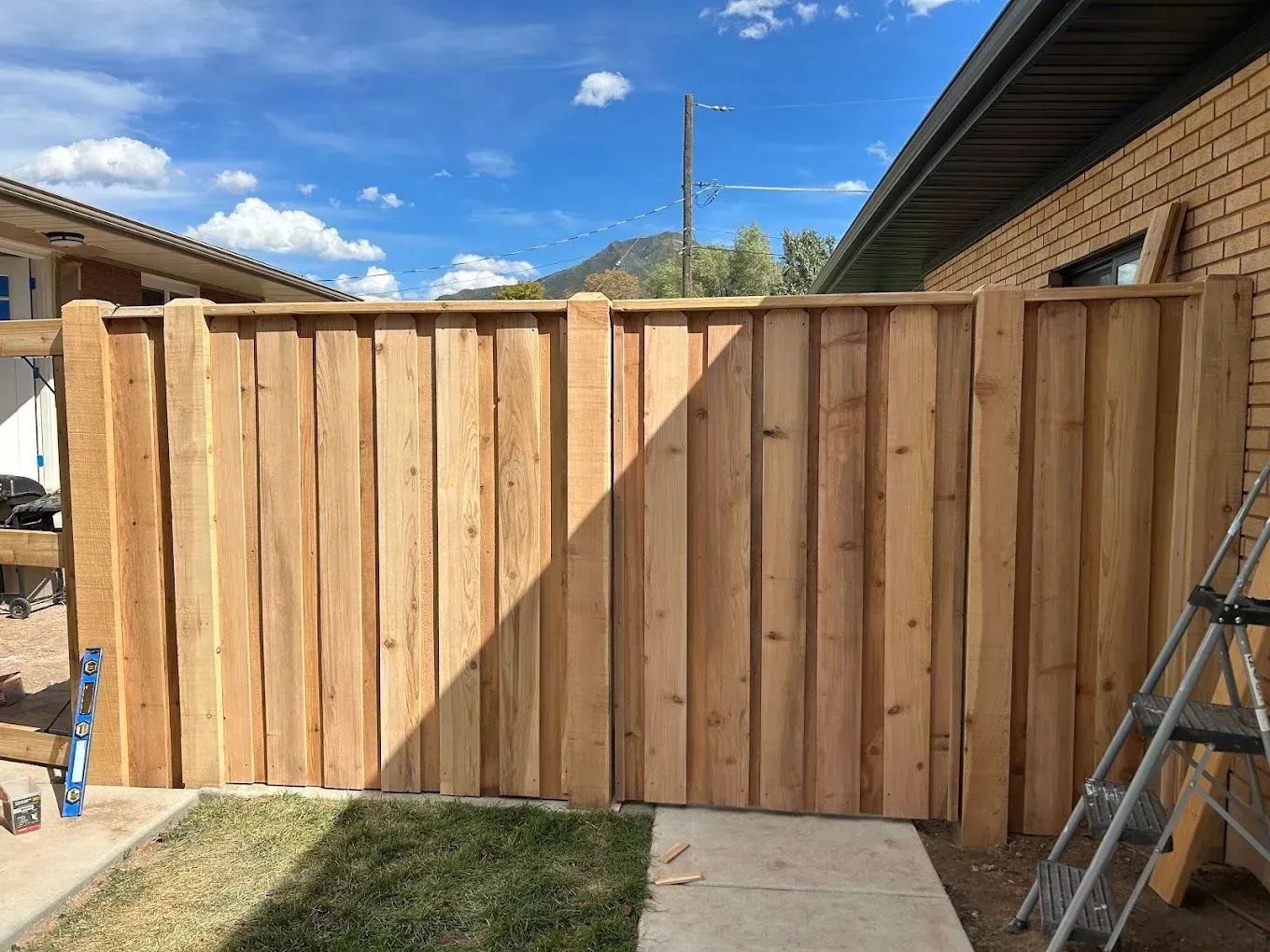 A wooden fence is being built in front of a brick house.
