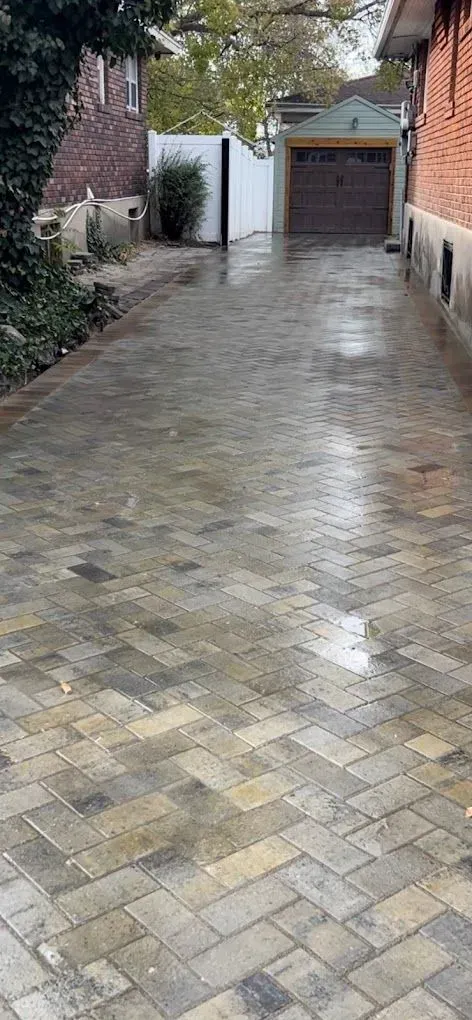 A brick driveway leading to a garage next to a brick house.