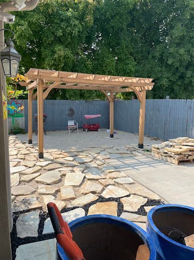 A wooden pergola is being built in a backyard.