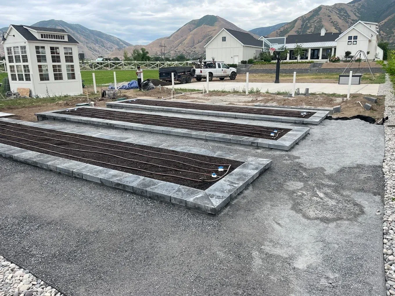 A row of planters are being built in a yard with mountains in the background.