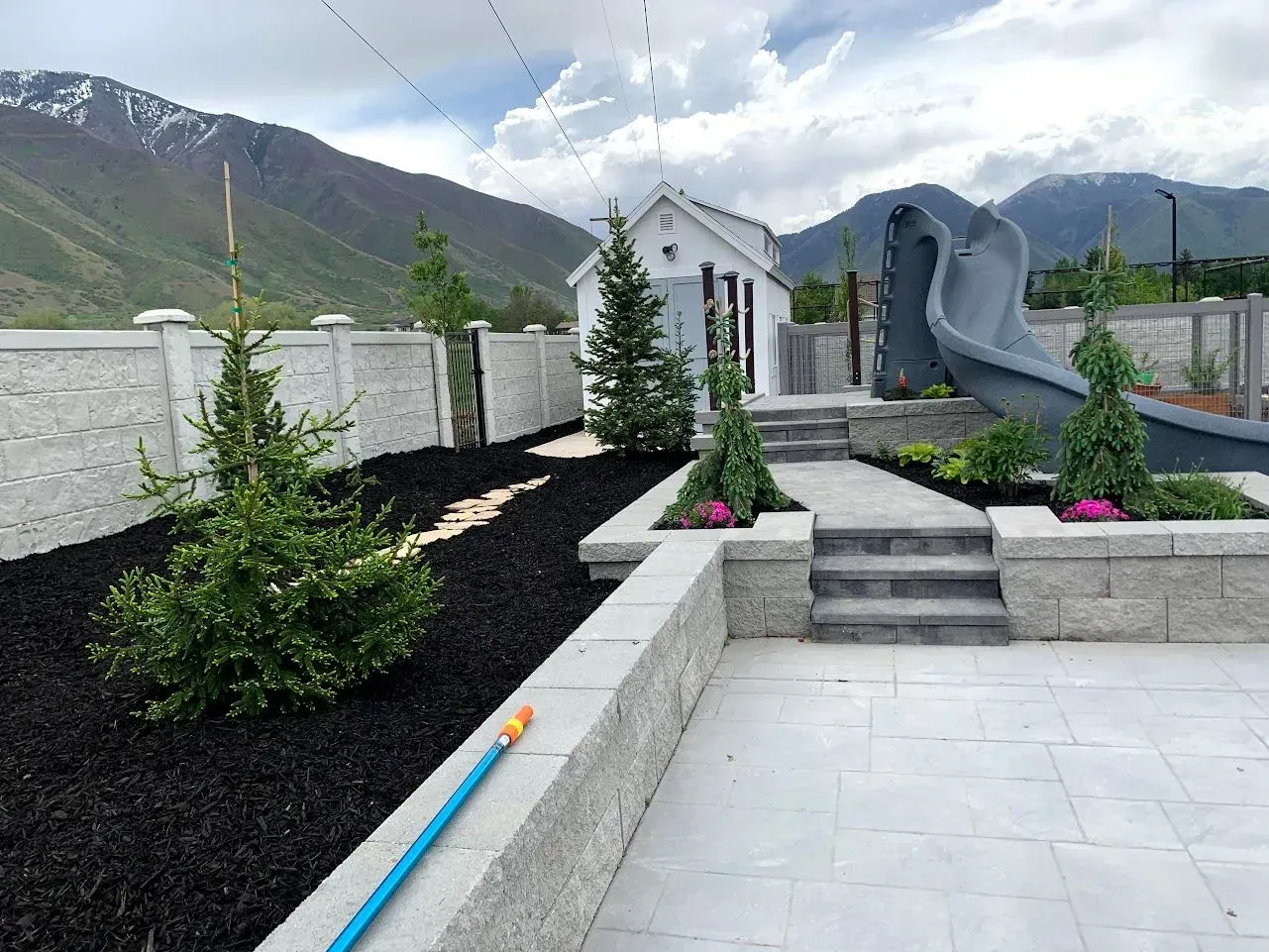 There is a slide in the backyard with mountains in the background.