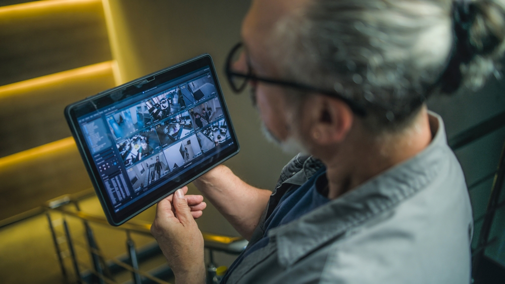 A man wearing glasses is looking at a tablet computer.