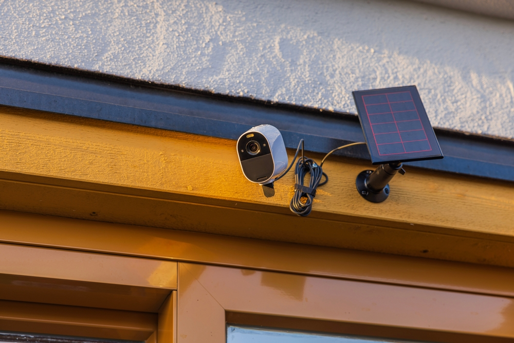 A security camera with a solar panel attached to it is on the side of a building.