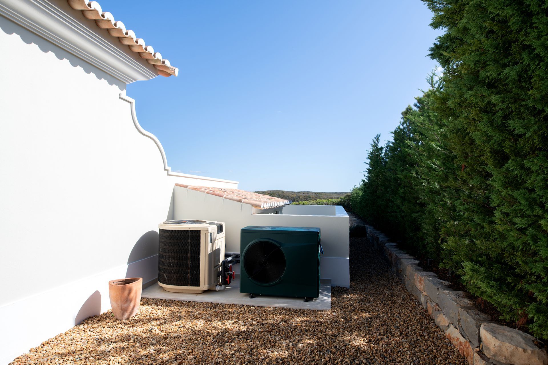 Two air conditioners are sitting outside of a house