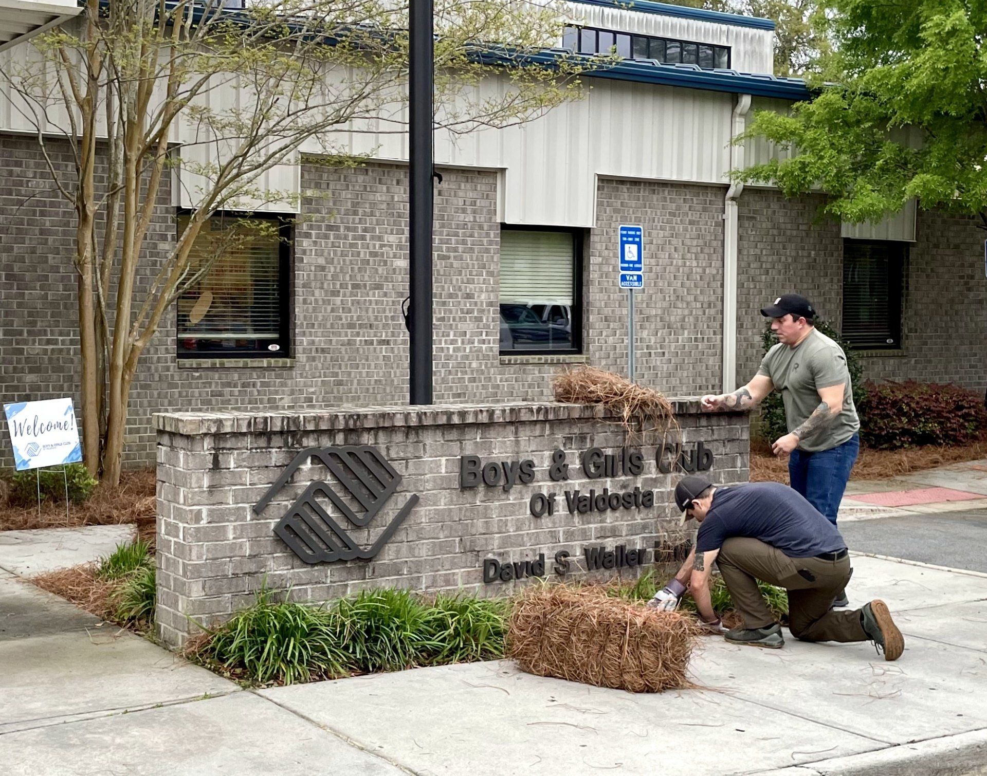 Adults working on landscape on the main entrance sign of the Boys & Girls Club of Valdosta building