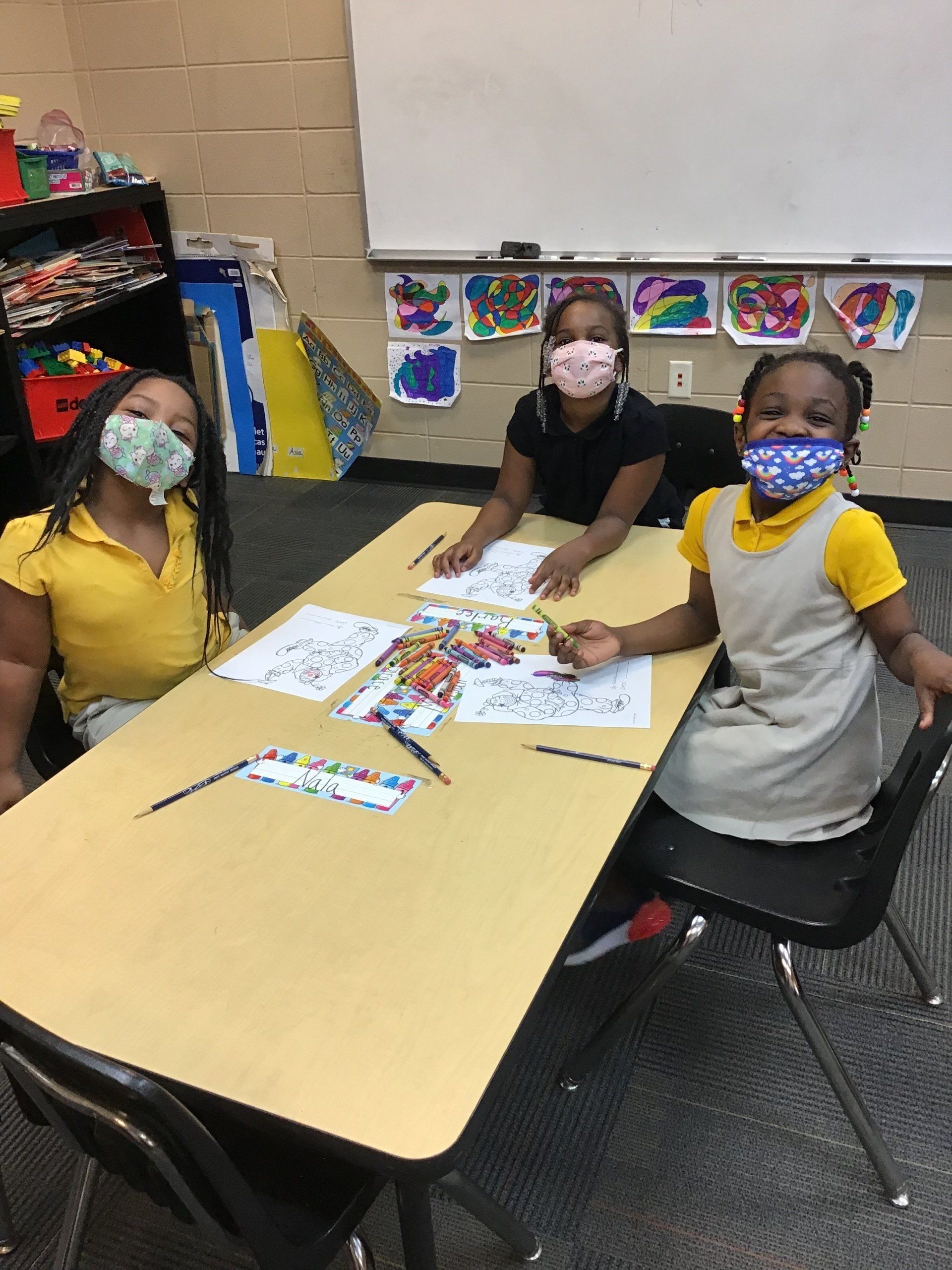 Three masked children at a table smiling at the camera at the Boys & Girls Club of Valdosta