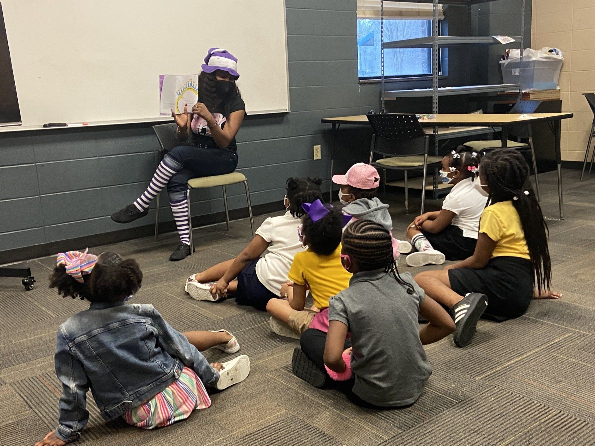 A group of kids sitting on the floor while their teacher reads them a book at Boys & Girls Club of Valdosta