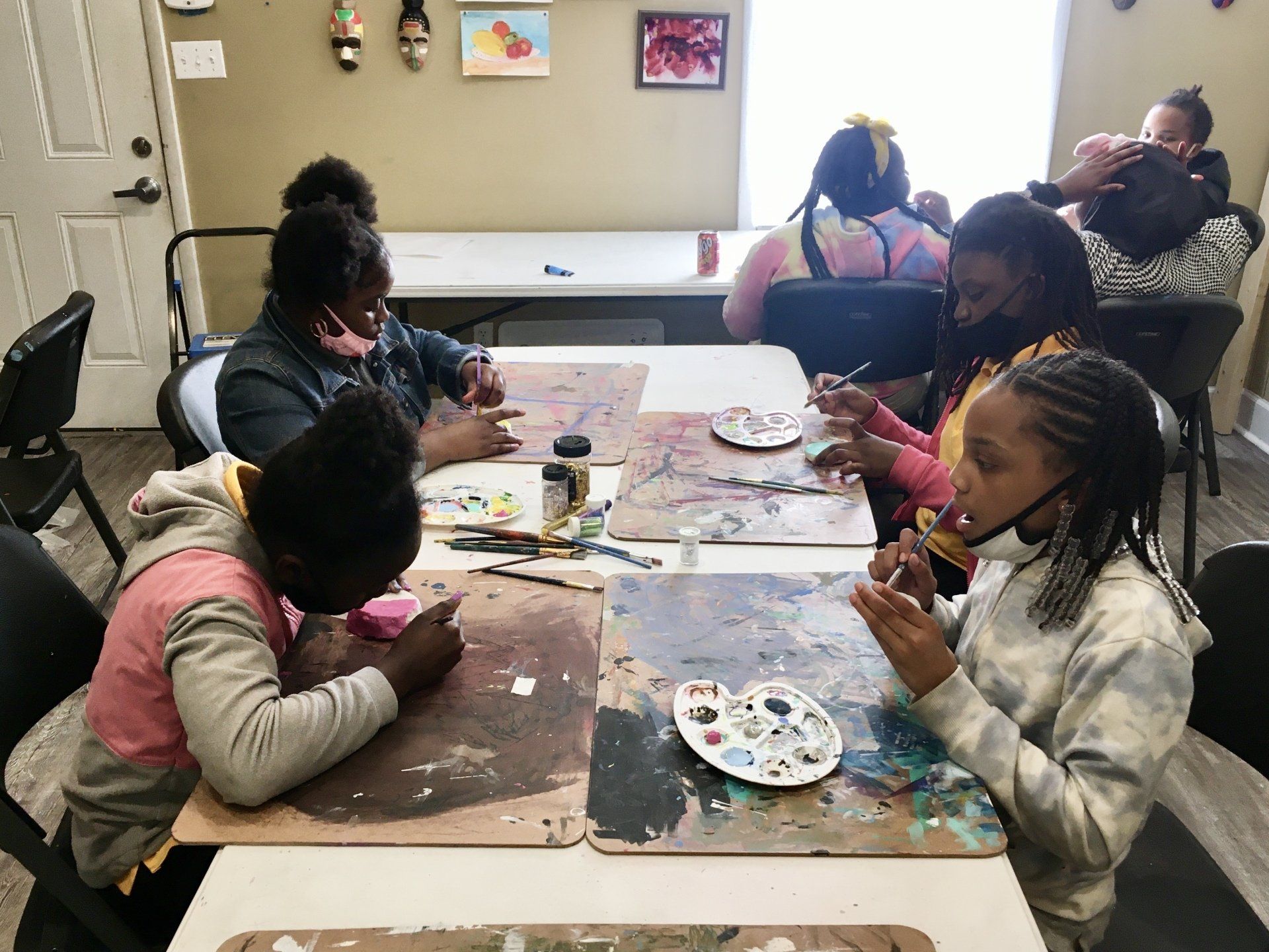 Kids sitting at tables painting craft projects at Boys & Girls Club