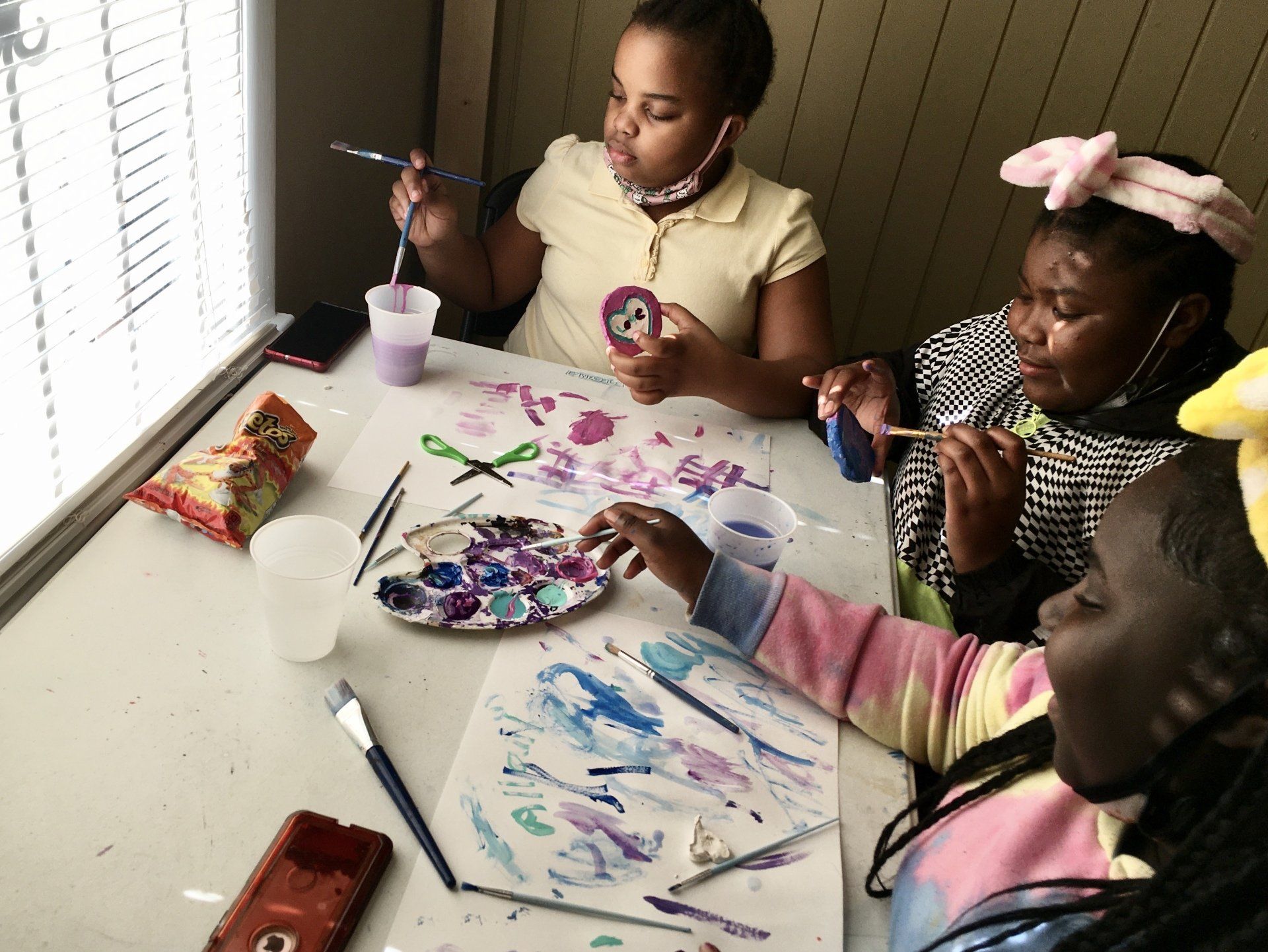 Staff member helping children with a painting activity at Boys & Girls Club