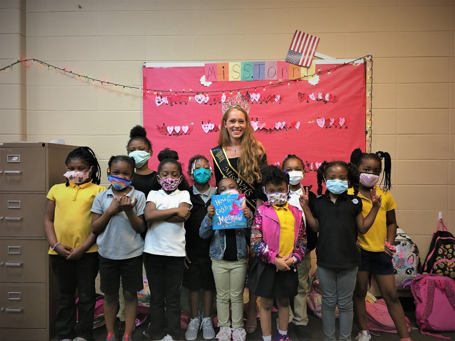 Class of young kids posing with a beauty pageant winner at Boys & Girls Club